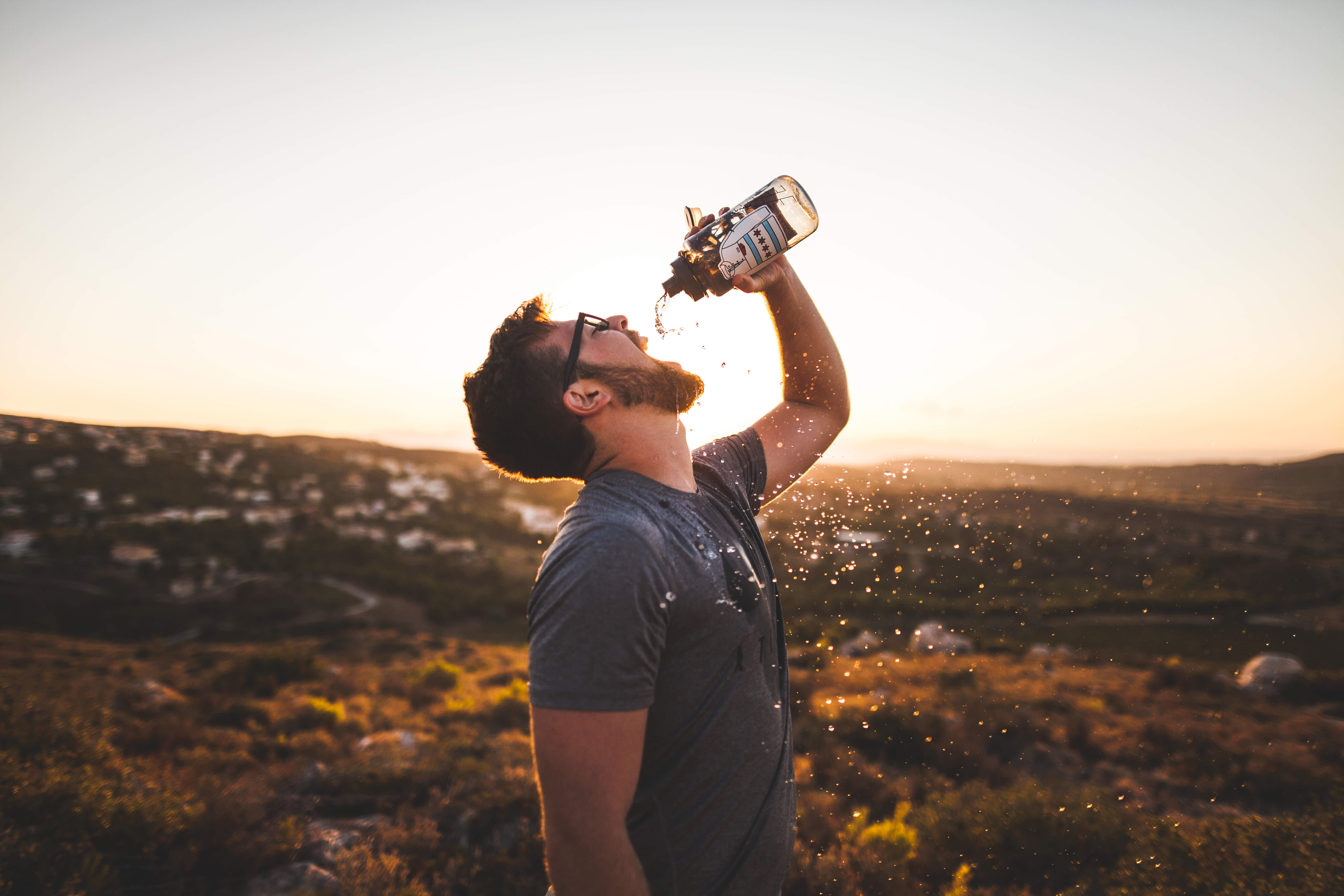 jeune homme buvant de l'eau par temps chaud